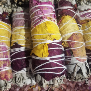 Picture of several white sage wrapped in rose petal smudge sticks